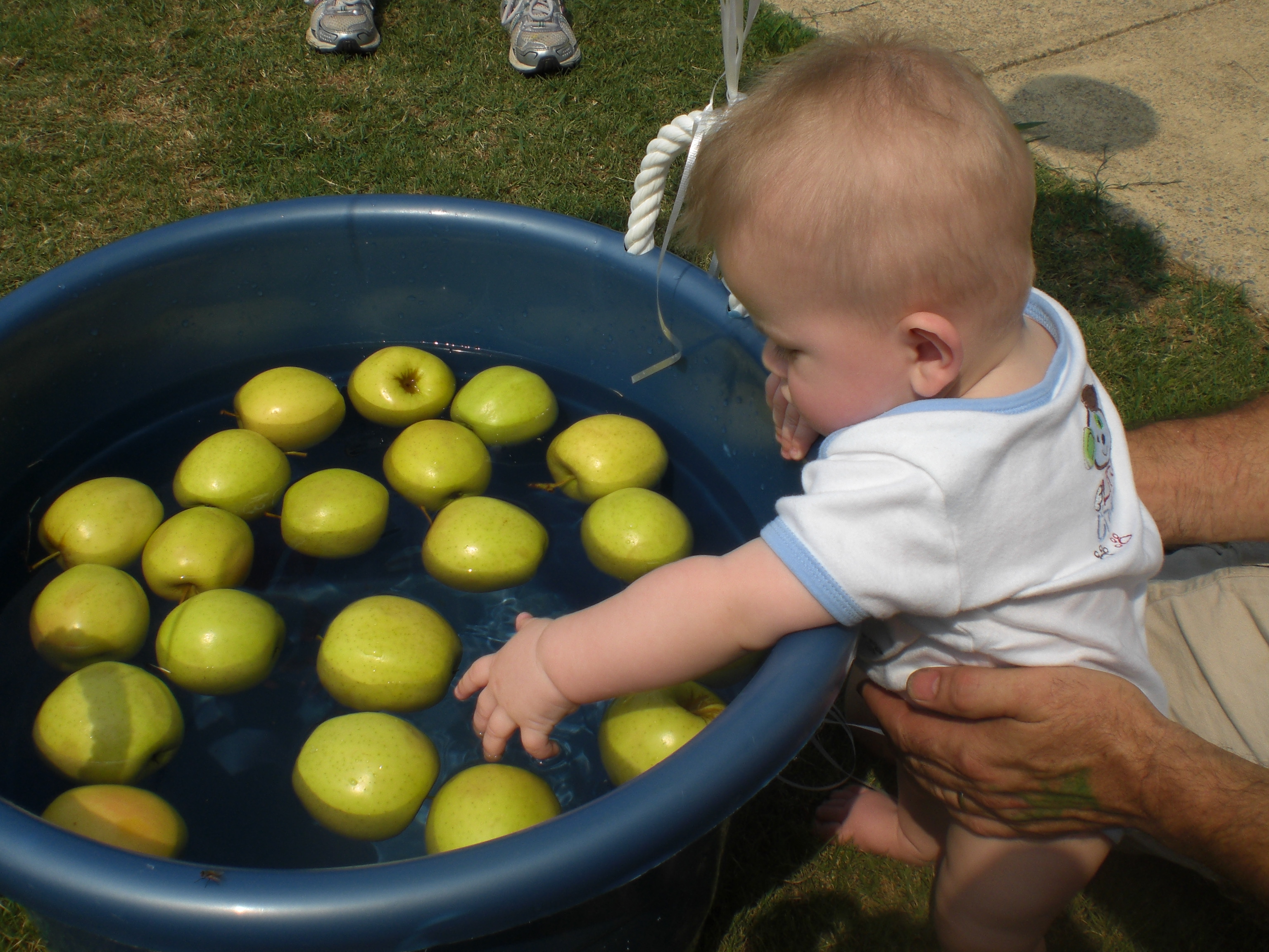 Un bambino cerca di prendere una mela con la mano sinistra